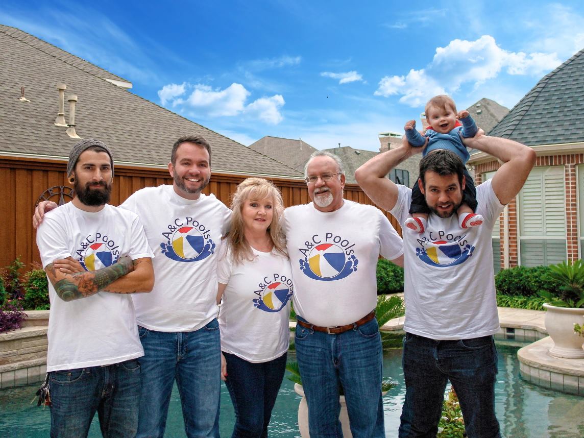 The A&C Pools family standing together beside a backyard pool