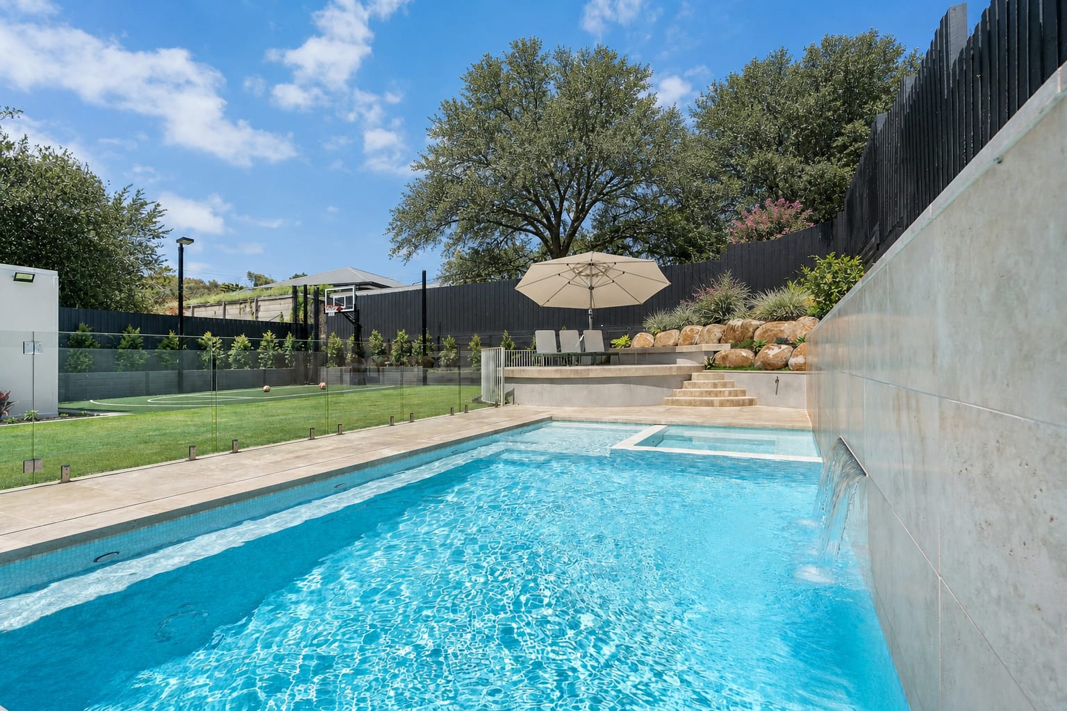 Clear residential pool with a raised spa and water feature